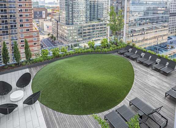 a green roof terrace with a lawn and city buildings