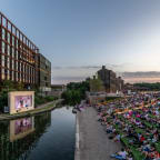 people watching a movie along the canal at sunset