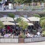 a large group of people sitting at tables under umbrellas