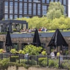 people sitting on the terrace of a building on the river thames in london