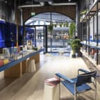 a view of the inside of a bookstore with wood floors and blue chairs