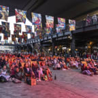 a crowd of people sitting in chairs in front of a building