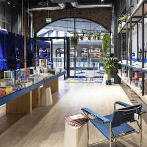 a view of the inside of a bookstore with wood floors and blue chairs