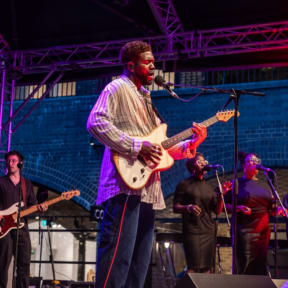 a man in a striped shirt is playing a guitar and singing into a microphone