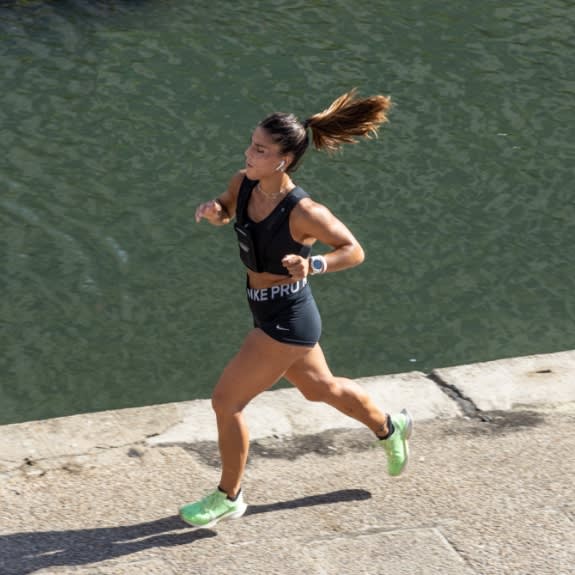 a woman running down a sidewalk next to a body of water