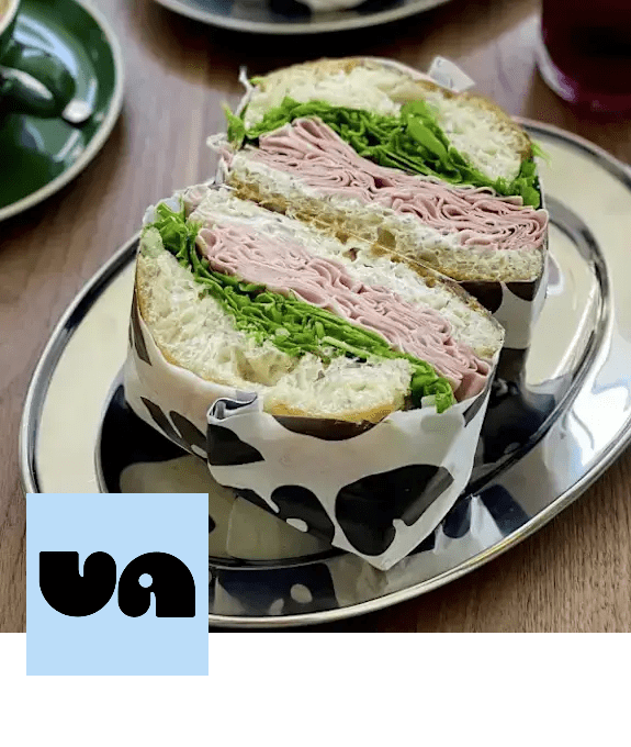 A sandwich with ham and lettuce is wrapped in paper and placed on a plate. at Citizen on Jasper, Alberta