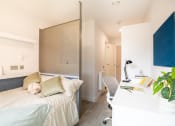 Thumbnail 1 of 8 - a bedroom with a bed and a desk and a workstation