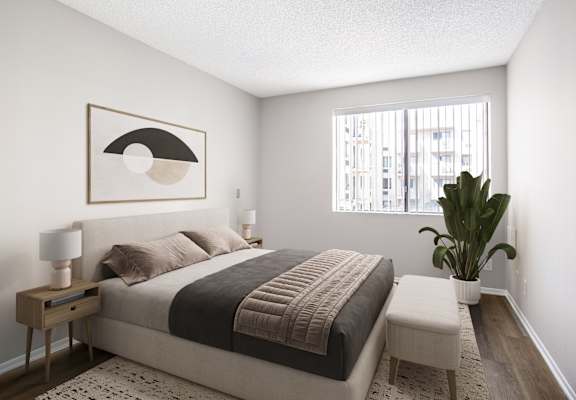 A bedroom with a bed, nightstand, and a plant.