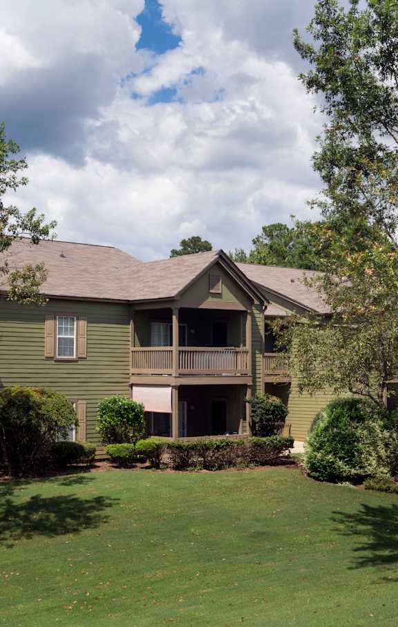 A green house with a balcony and a tree in front at Austin Chase Apartments, Macon