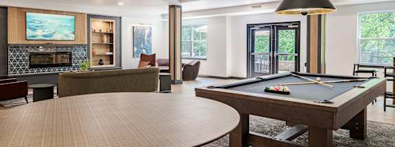 A billiard table is in the middle of a room with a fireplace and a television.
