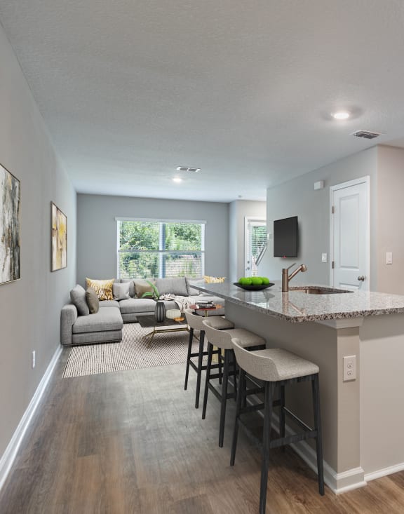 an open kitchen and living room with an island and stools