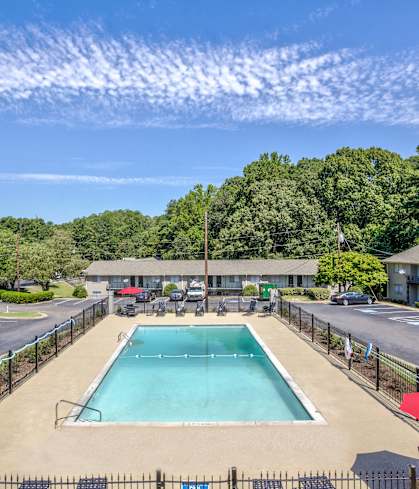 a swimming pool with an umbrella next to a parking lot