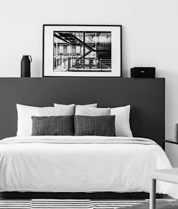 A black and white bedroom with a large bed and a framed picture above it.
