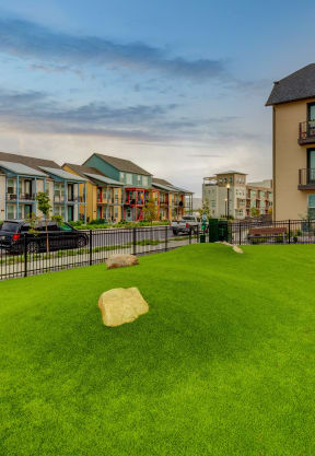 a yard with a rock on the grass in front of some houses