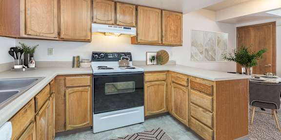 A kitchen with white appliances and brown cabinets.