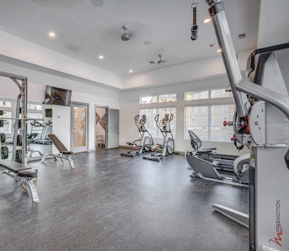 a gym with weights and cardio equipment in a building with windows