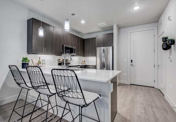a kitchen with a large island with three chairs