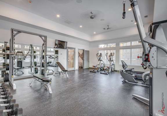 a gym with weights and cardio equipment in a building with windows