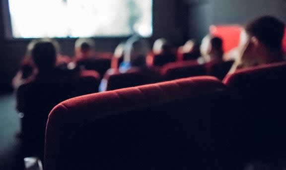 people sitting in a auditorium watching a presentation on a screen