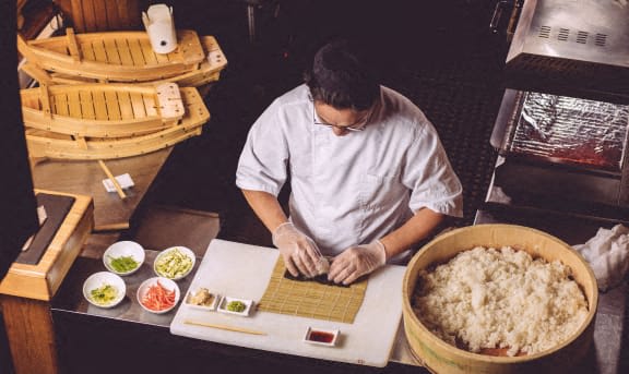 a man working on a laptop in front of a table of food