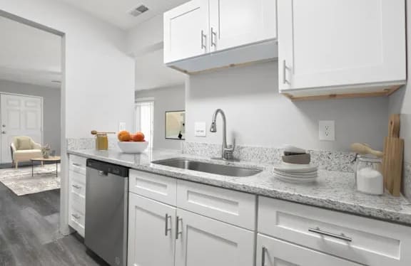 A modern kitchen with white cabinets and a marble countertop.