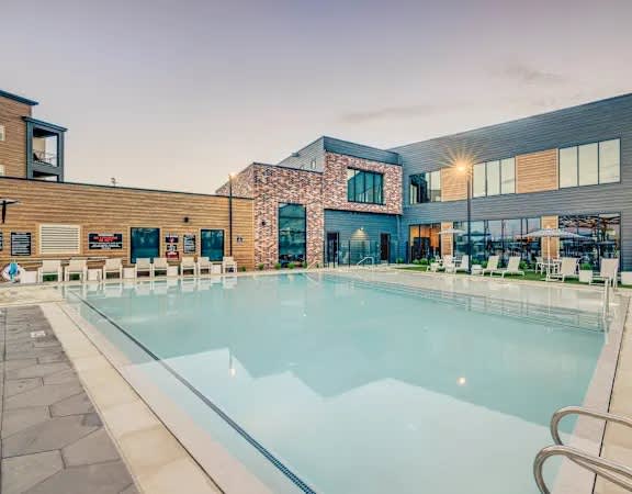 A large indoor swimming pool with a glass barrier and a stone walkway.