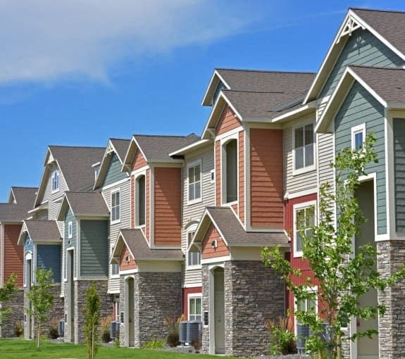 a row of houses with siding and a green lawn