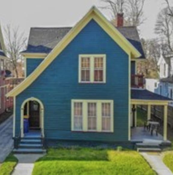 a blue house with a porch and a lawn