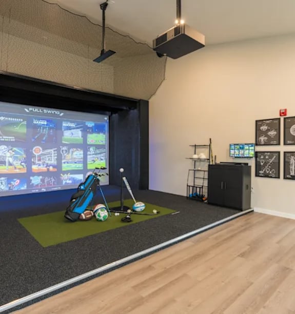 A room with a VR setup and golf equipment.