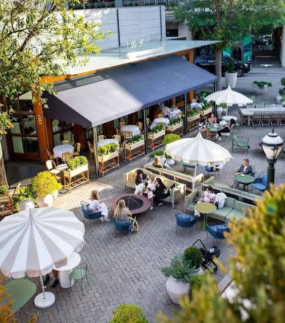 A patio with tables and chairs and umbrellas.