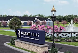 A sign for Grand Villas leans against a black post.