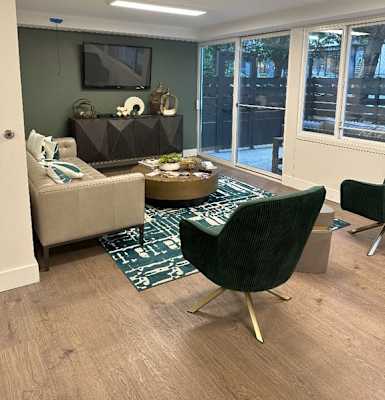 A living room with a green rug and a black chair.