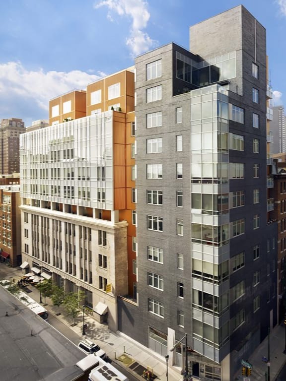 A modern multi-story building with a mix of glass and solid panels.