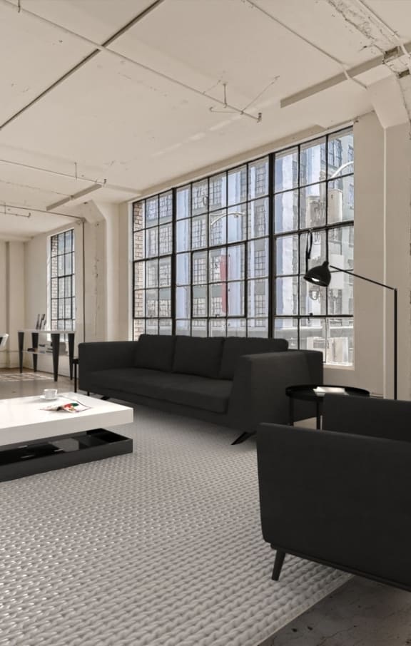 A modern living room with a grey carpet and black furniture.