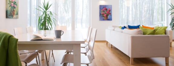 a living room with a table and chairs and a couch in front of a window