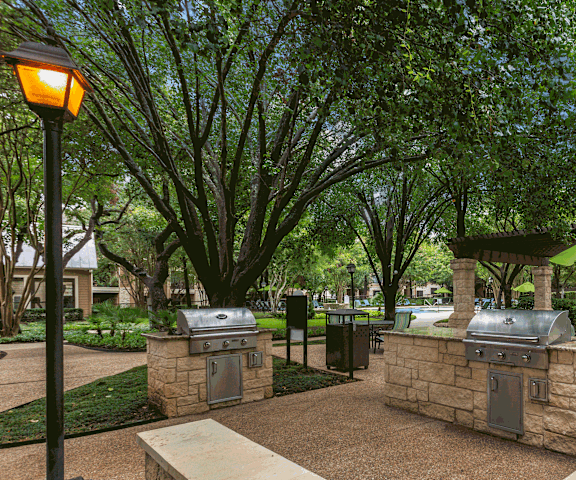 a bbq area with two grills and a table with a green umbrella at Ventana Oaks Apartments, Austin, TX, 78717