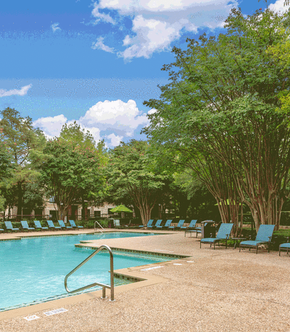 a swimming pool with chaise lounge chairs and trees