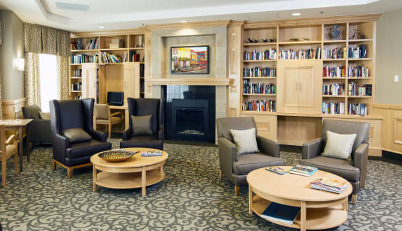A reading room with comfortable chairs, fireplaces, and coffee tables.