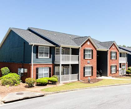 A row of townhouses with a car parked in front of the first one at Ballantyne Commons of Stockbridge Apartments, GA, 30281