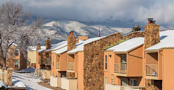 A row of houses with snow on the roofs and trees.
