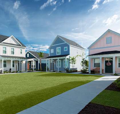 a row of blue and white homes with a green lawn