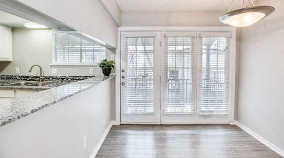 A kitchen with a marble countertop and white cabinets.