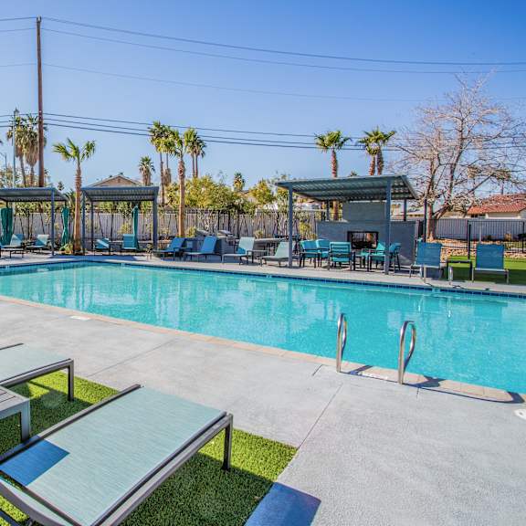 A pool area with sun loungers and umbrellas.