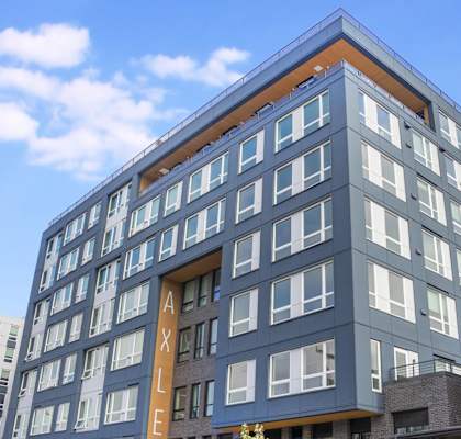 A modern building with a blue and orange facade and a large window.at Axle, Seattle Washington