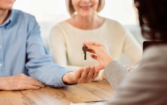 A person is handing over a key to another person.