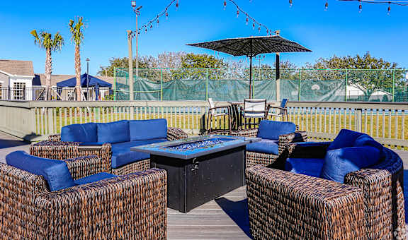 A patio with blue cushions and a black umbrella.