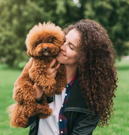 a woman holding a brown dog in a park