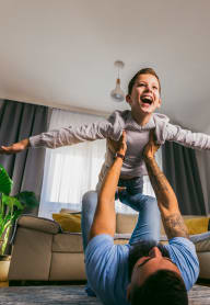 a man holding a child in the air in a living room