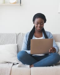 a woman sitting on a couch using a laptop