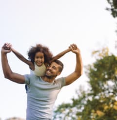 a man carrying a young girl on his shoulders
